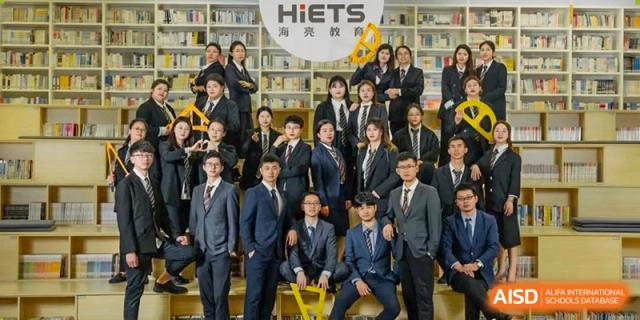 A group of students at HAILIANG FOREIGN LANGUAGE SCHOOL poses for a photo in front of a bookshelf.