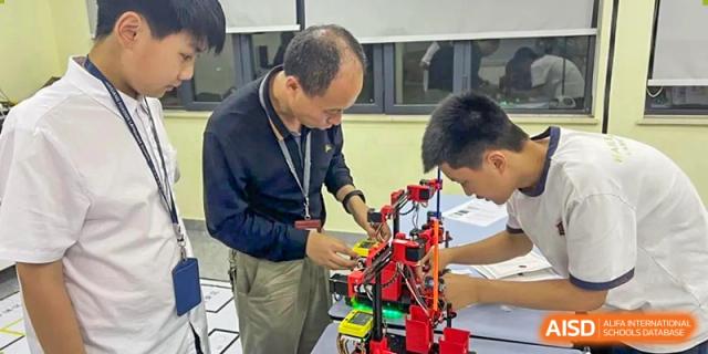 A teacher at HAILIANG FOREIGN LANGUAGE SCHOOL helps students with a robotics project.