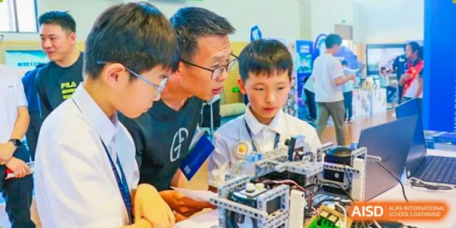 A teacher at HAILIANG FOREIGN LANGUAGE SCHOOL helps students with a robotics project.
