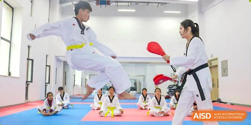 Students at HAILIANG FOREIGN LANGUAGE SCHOOL practice Taekwondo, with one student kicking a board.