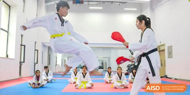 Students at HAILIANG FOREIGN LANGUAGE SCHOOL practice Taekwondo, with one student kicking a board.