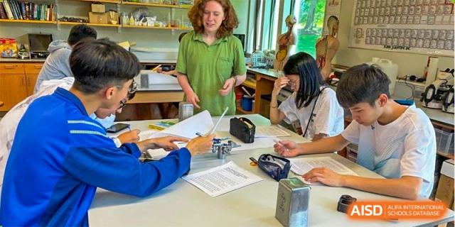 A group of students working on a hands-on project at a table with an adult at HD Qingdao School.