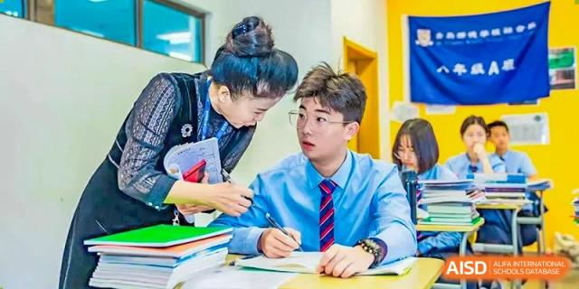 A teacher helping a male student with his work at a desk at HD Qingdao School.
