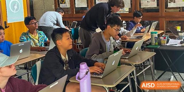 Two students working on laptops in a modern classroom at HD Qingdao School.