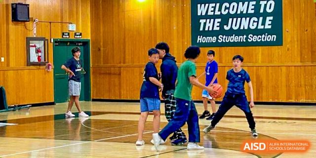 A basketball practice in a school gym with four students in athletic gear HD Qingdao School.