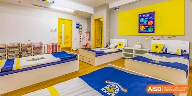 A dormitory room with two beds with blue and yellow bedding and a large yellow cabinet at HD Qingdao School.