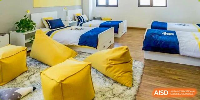 A dorm room with two beds, large windows, and a yellow bean bag chair at HD Qingdao School.