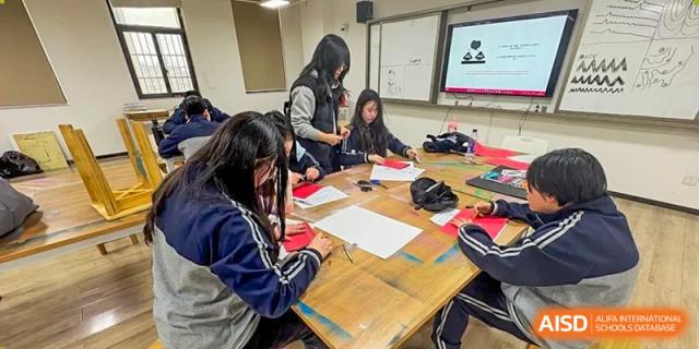 Students from Hongyi Cambridge International School (HYCIS) working collaboratively on a project or assignment around a table.