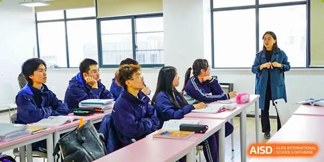 A group of students from Hongyi Cambridge International School (HYCIS) seated at a long table, attentively participating in a class discussion.