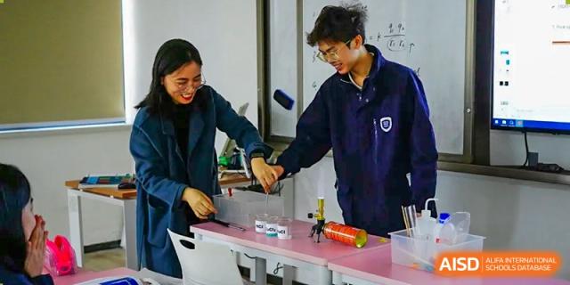 Two students from Hongyi Cambridge International School (HYCIS) smiling while working on a hands-on science experiment in a laboratory.