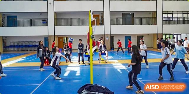 Students from Hongyi Cambridge International School (HYCIS) playing an indoor volleyball game in the gymnasium.