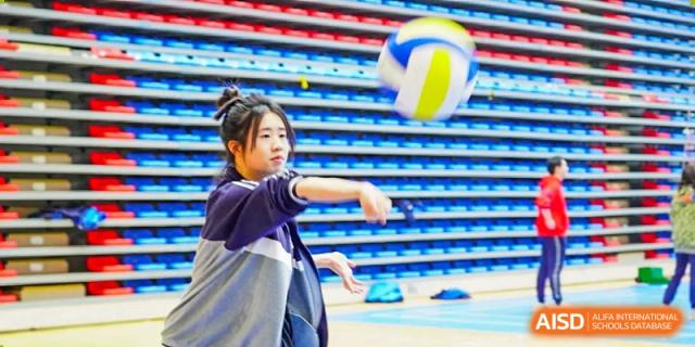 A student from Hongyi Cambridge International School (HYCIS) hitting a volleyball during a game or practice.