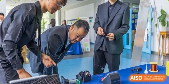 An adult helps students with a robotics project in a classroom at the International School of Qingdao.