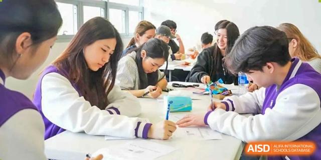 Students work together in a group on a project at a table at the International School of Qingdao.