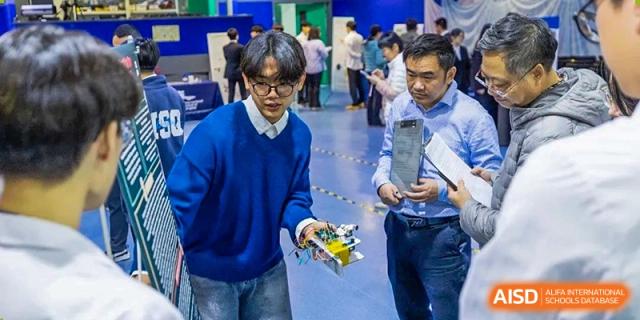 Students show a judge their robot during a competition at the International School of Qingdao.