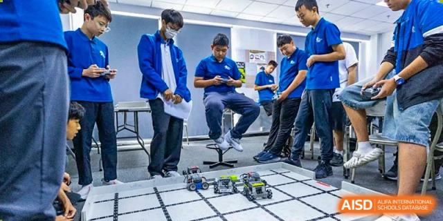 Students sit and stand around a robot on a competition mat at the International School of Qingdao.