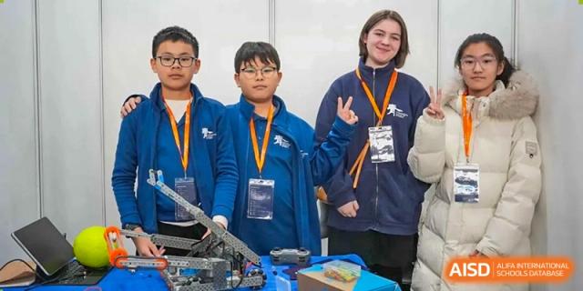 Students with lanyards pose with their robot at a competition at the International School of Qingdao.