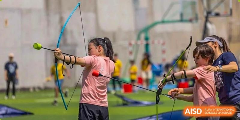 A student practices archery on a field at the International School of Qingdao.