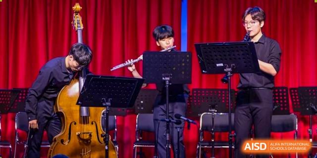 A student plays the flute on stage during a musical performance at the International School of Qingdao.