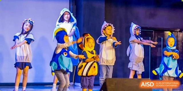 Students in fish costumes perform on a stage during a school play at the International School of Qingdao.