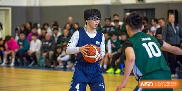 A basketball player holds a basketball on the court during a game at the International School of Qingdao.