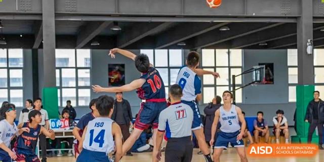 Students play basketball in a gymnasium during a game at the International School of Qingdao.