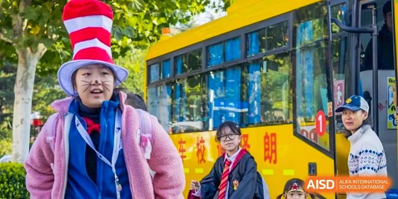 A student in a wizard costume stands in front of a yellow building at the International School of Qingdao.