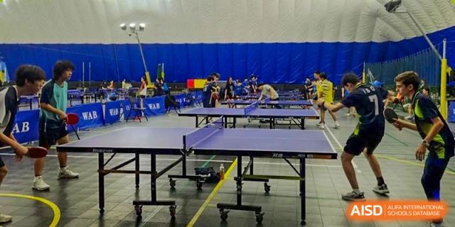 Students play ping pong in a gym at the International School of Qingdao.
