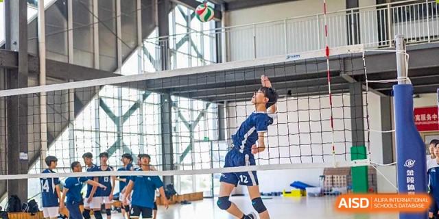 A male volleyball player jumps in the air to hit the ball at the International School of Qingdao.