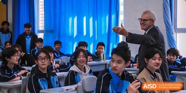 Students smiling and engaged while interacting with a teacher in a classroom at the International Department of Kunming No.10 Middle School.