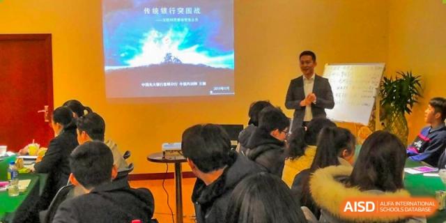 A speaker presenting to students in a dark room during a lecture at the International Department of Kunming No.10 Middle School.