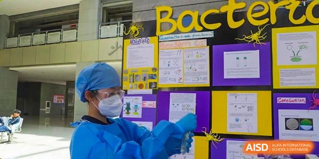 A student in blue protective gear and safety glasses working on a science project at a fair for the International Department of Kunming No.10 Middle School.