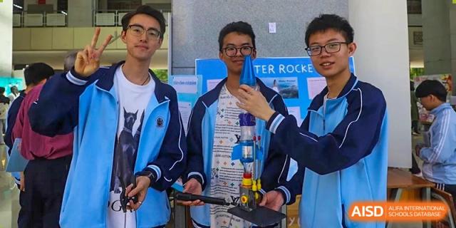 Three male students proudly holding a student-made water rocket outside at the International Department of Kunming No.10 Middle School.