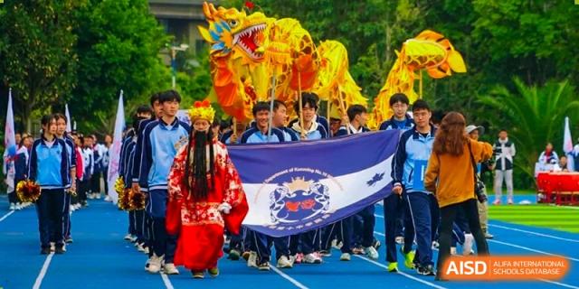 Students with a banner, a person in a traditional costume, and a dragon dance prop at the International Department of Kunming No.10 Middle School.