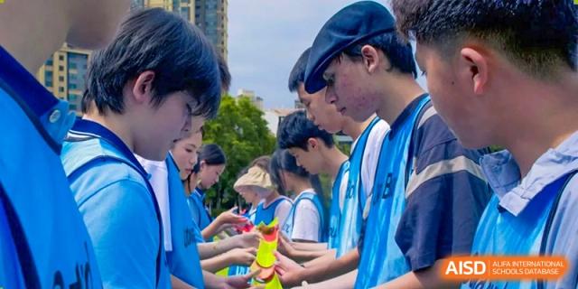 A line of students in light blue shirts concentrating on a team game during a competition at the International Department of Kunming No.10 Middle School.