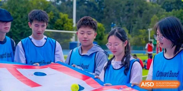 Two students holding a banner and preparing for an activity during a field day at the International Department of Kunming No.10 Middle School.