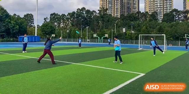 A student throwing a frisbee during an outdoor activity on the sports field at the International Department of Kunming No.10 Middle School.