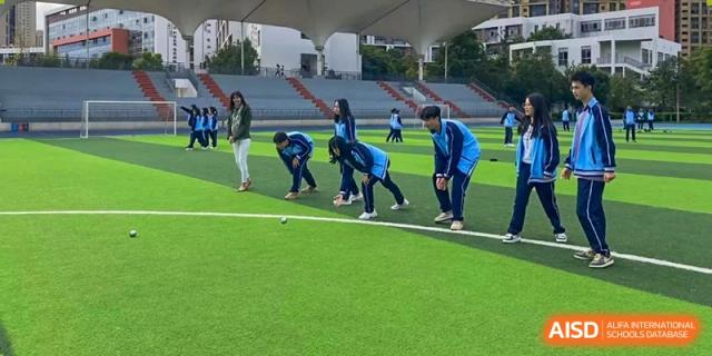 Students playing a field game in blue uniforms on the green turf at the International Department of Kunming No.10 Middle School.