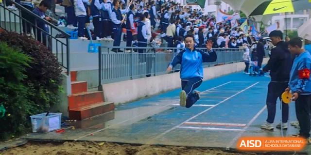 A student completing a long jump landing in the sand pit at the International Department of Kunming No.10 Middle School.
