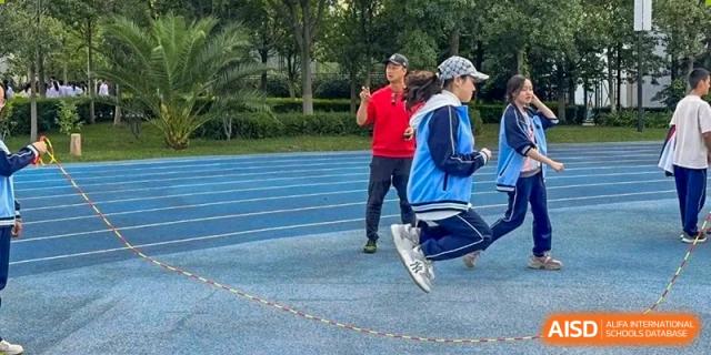 A student mid-jump on a blue running track during a sports activity at the International Department of Kunming No.10 Middle School.