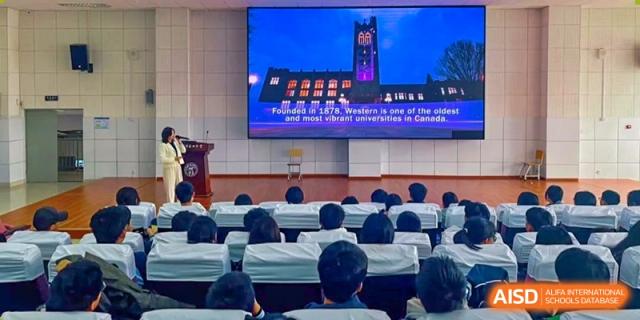 Students attending a presentation with a slide showing a university building at the International Department of Kunming No.10 Middle School.