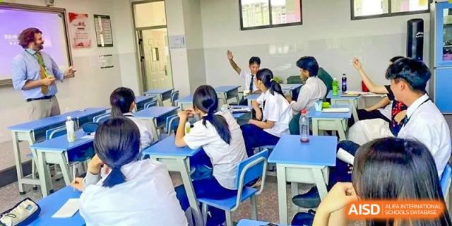 Students raising their hands in a classroom at Kunming World Youth Academy.
