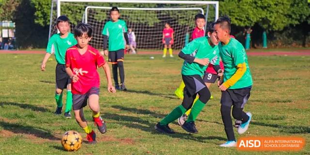 Students playing a field game, possibly a variation of soccer, at Kunming World Youth Academy.
