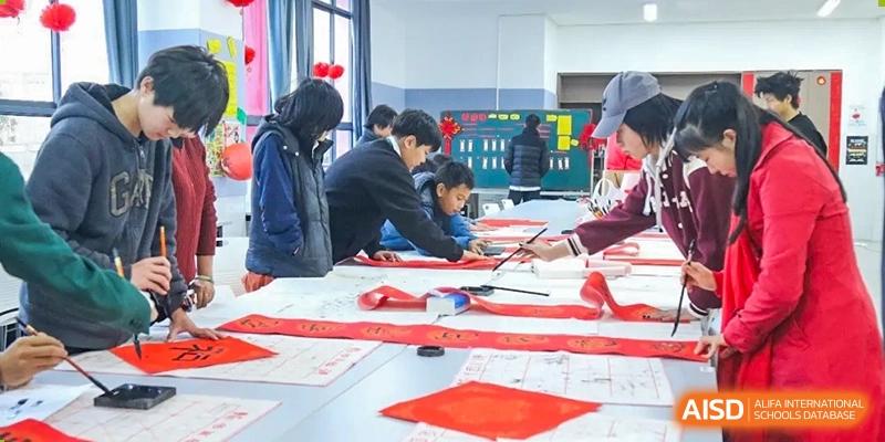 Students creating art with red paper at Kunming World Youth Academy.