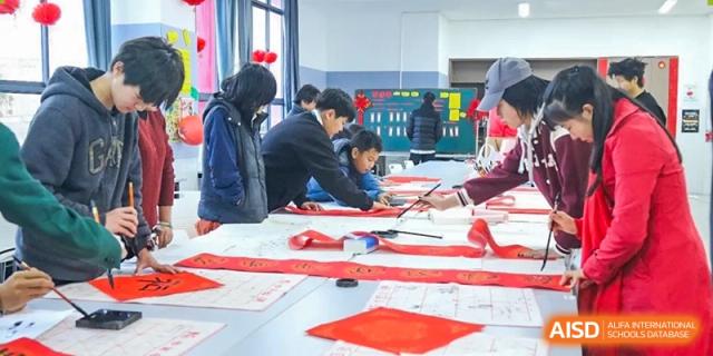 Students creating art with red paper at Kunming World Youth Academy.