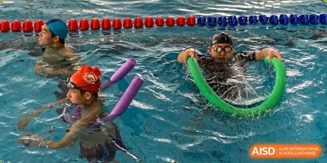 A student swimming with pool noodles in a class at Kunming World Youth Academy.
