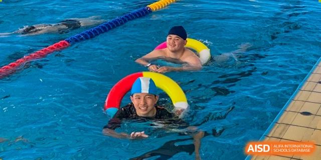 Students learning to swim with colorful floats at Kunming World Youth Academy.