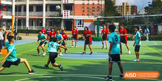 Students playing a field game, possibly soccer or a similar sport, at Kunming World Youth Academy.
