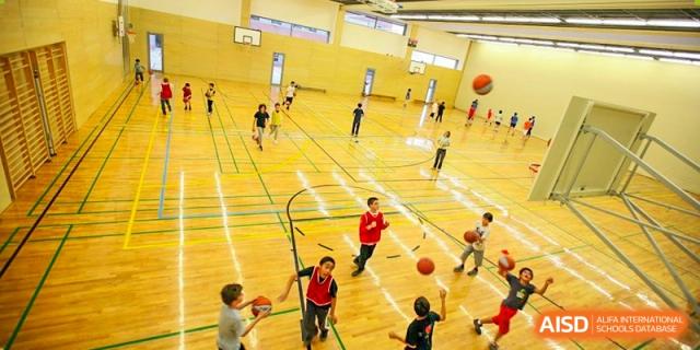 A group of Lycée Français de Shanghai students is playing basketball in a spacious gymnasium.