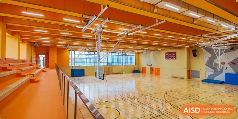 A bright, empty sports hall at Lycée Français de Shanghai is shown with a basketball court and high ceilings.